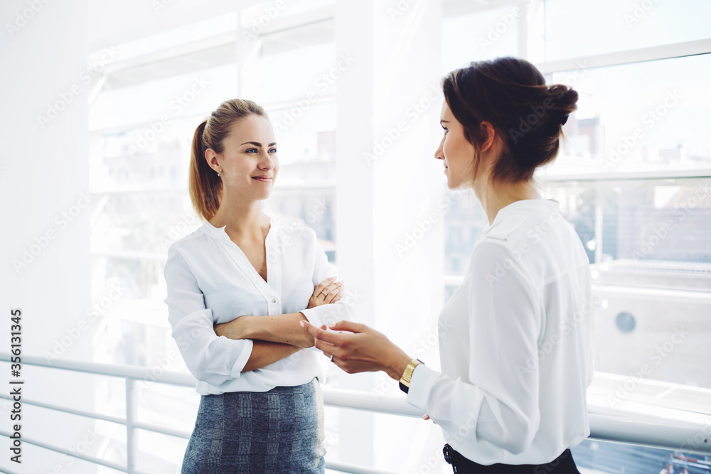 Two female employees having pleasant conversation after analyzing strategy on digital tablet