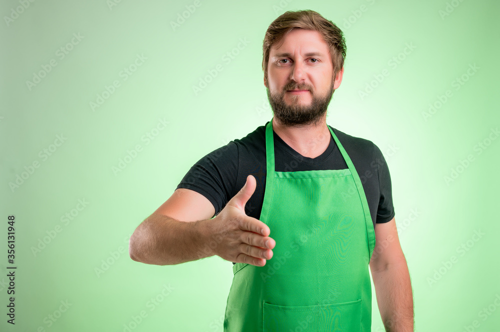 Supermarket employee with green apron and black t-shirt shaking hand Supermarket employee with green apron and black t-shirt shaking hand