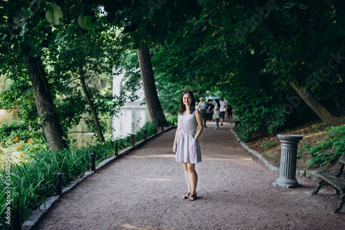 Sofia Park, Uman. Girl in a summer board on the alley of the park. Smiling brunette girl on a stone alley near the lake. Walk in the park, a large beautiful lake.