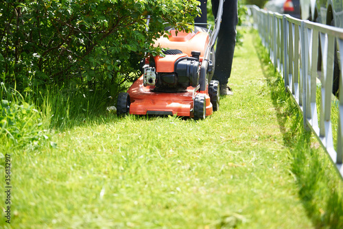 a close-up lawnmower mows the green grass on the lawn.Bright Sunny day