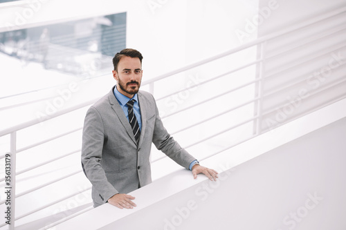 Male intelligent CEO is waiting business partners in hallway his company