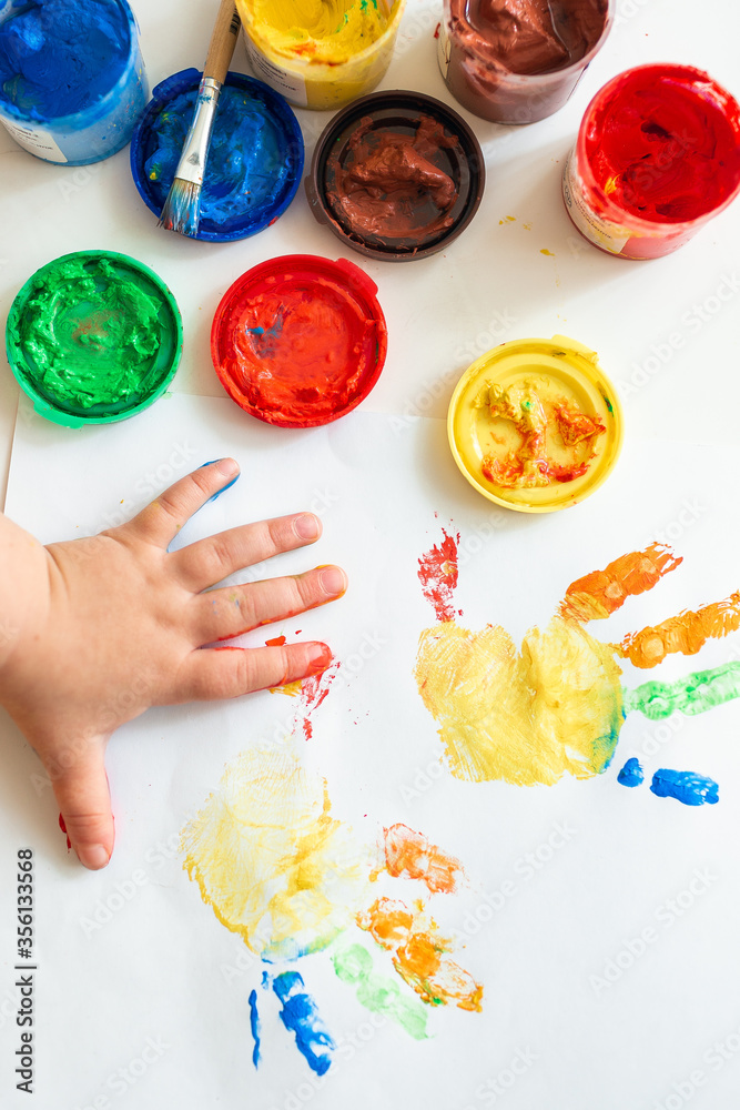 Close up of colored hand print on white background. Ideas for drawing with finger  paints. Finger painting for kids. Little girl painting by finger hand paint  color. Children development concept. Stock Photo