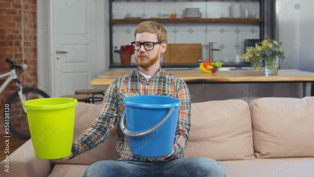 Man Using Buckets For Collecting Water Leakage From Ceiling Man Using Buckets For Collecting Water Leakage From Ceiling