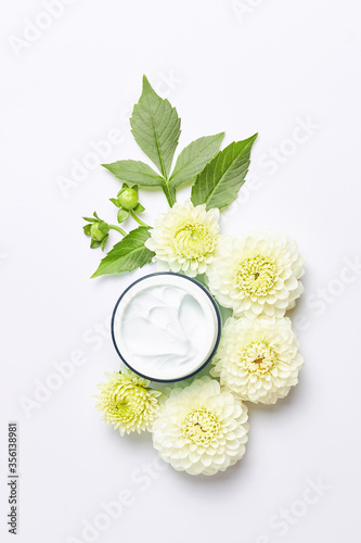 spa concept or template. florals compositions made white flowers and skincare cream. vertical frame, top view concept
