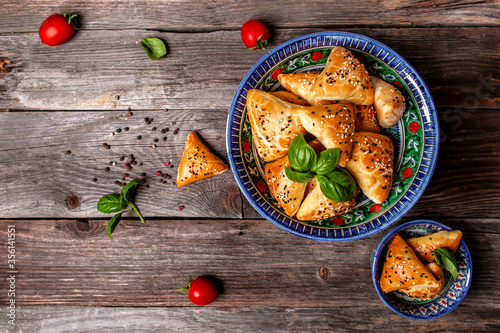 Uzbek national dish samosa. Indian samosas baked pastry with savoury filling, popular Indian snacks, served in bowl with spices on rustic background, top view photo