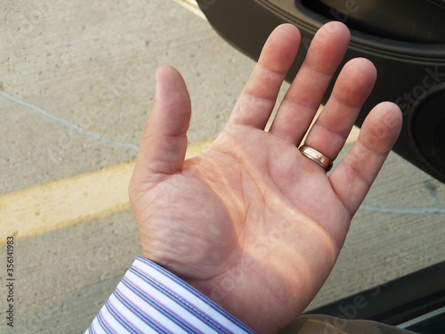 man's hand with gold ring and car door
