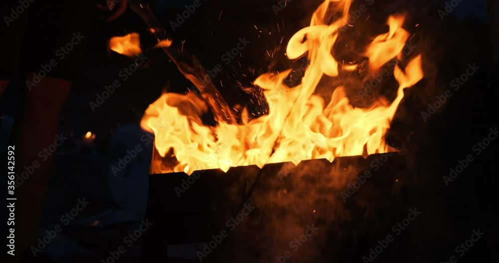 Big bright flame, fire, a bonfire with lights, sparks, ash and smoke in slow motion. Preparing coal for bbq grill in the dark. A rapid campfire blaze in red and orange hot vibrant colors in outdoor Big bright flame, fire, a bonfire with lights, sparks, ash and smoke in slow motion. Preparing coal for bbq grill in the dark. A rapid campfire blaze in red and orange hot vibrant colors in outdoor