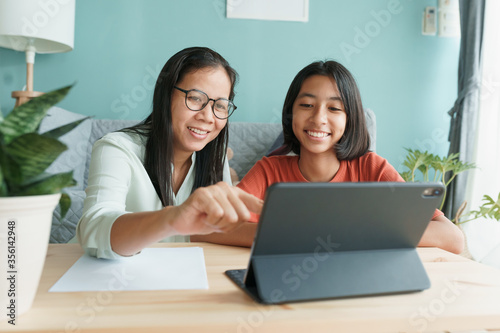 Asian family with daughter do homework by using tablet with mother help. 
