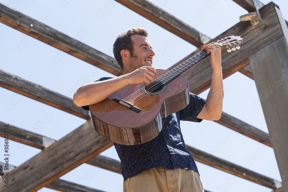 Man playing a Spanish guitar with a happy expression Man playing a Spanish guitar with a happy expression