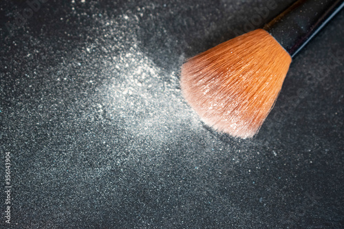 Make up brush with powder on black background
