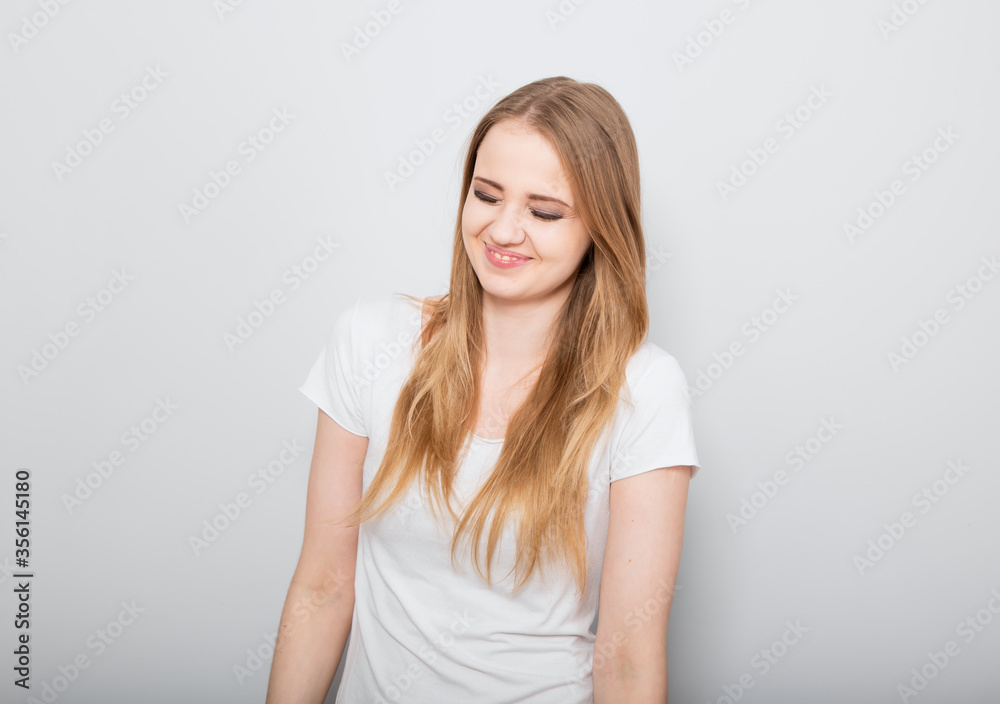 Pretty smiling joyful young woman with fair blond long hair in casual dress looking with happy. Studio shot of good looking beautiful woman isolated against grey studio wall Pretty smiling joyful young woman with fair blond long hair in casual dress looking with happy. Studio shot of good looking beautiful woman isolated against grey studio wall