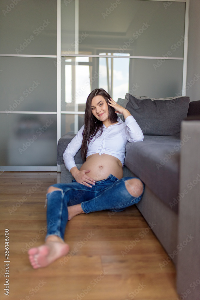 Beautiful pregnant girl is sitting on the floor.