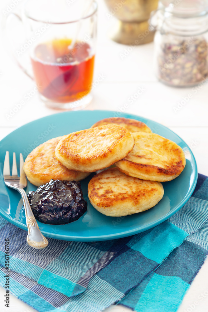 Cheese panecakes on blue plate with jam and tea