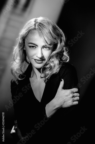 Monochrome fashion portrait of beautiful blonde woman in glamour black dress