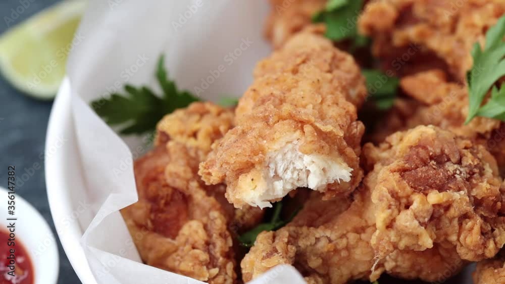 Eating crispy fried chicken in a white bowl with tomato sauce. Eating crispy fried chicken in a white bowl with tomato sauce.