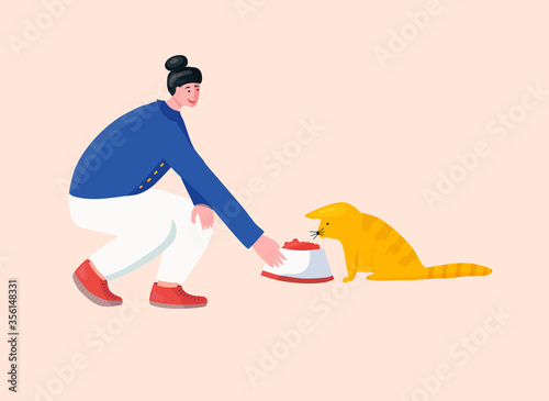 Girl volunteer feeding lost cat in animal shelter.