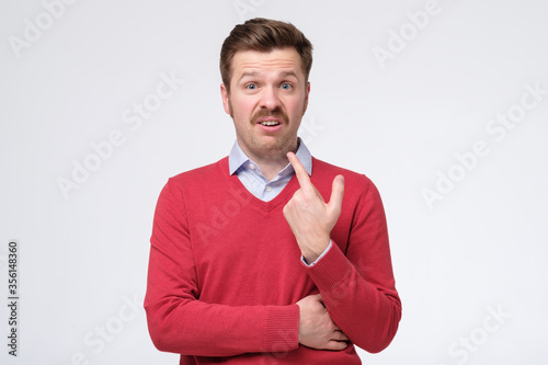 puzzled man indicates at himself with wondered expression, asks who me photo