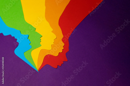 The human rainbow colored paper profiles cut out on a purple background. There is a place for text. The photo of paper art was made for your design.