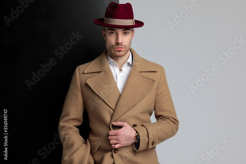 sexy young man wearing hat and adjusting longcoat photo