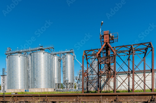 Round metal grain elevator bins next to railroad