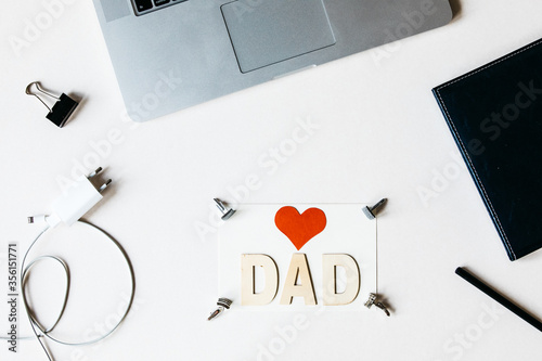 Dad I love you message. Greetings for Father's Day.  Laptop, charger and notebook top view. Happy Fathers Day background with stylish office utensils. Overhead view. Business man. Father at work