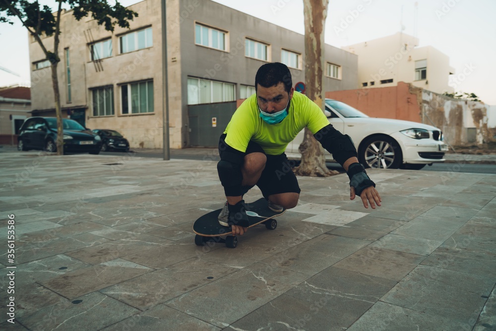 Young man with a mask on his face skating with skateboard in the street