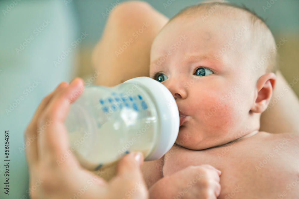 Closeup of a mother feeding baby with milk bottle at home Closeup of a mother feeding baby with milk bottle at home
