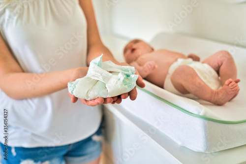 Photographie A mother Changing Baby's Diaper In nursery holding diaper