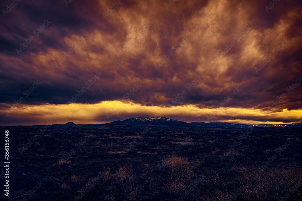 Surreal post-apocalyptic edit of a wasteland with fire red and yellow burning cloudy sky in the wake of a virus apocalypse. The stormy dark sky beckons in the viral anxiety of a dark pestilence. 