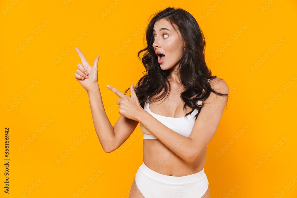 Image of young surprised woman in swimsuit pointing fingers aside Image of young surprised woman in swimsuit pointing fingers aside