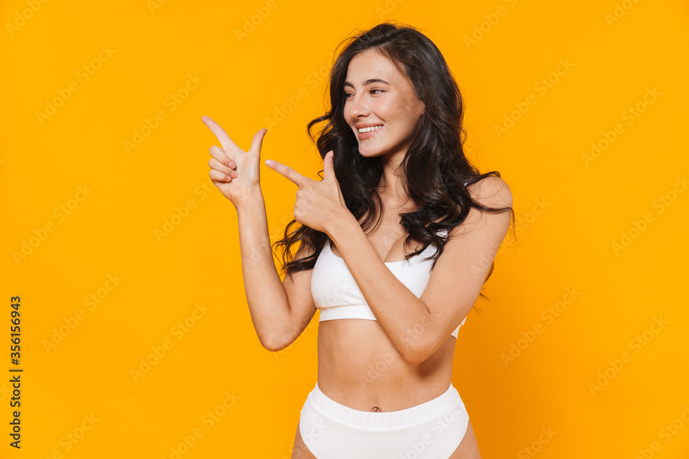 Image of young pleased woman smiling and pointing fingers aside Image of young pleased woman smiling and pointing fingers aside