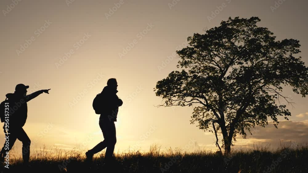 Teamwork. Travelers with backpacks are walking across the field at sunset. Travelers enjoy the scenery, lead a healthy lifestyle. Teamwork. Travelers with backpacks are walking across the field at sunset. Travelers enjoy the scenery, lead a healthy lifestyle.
