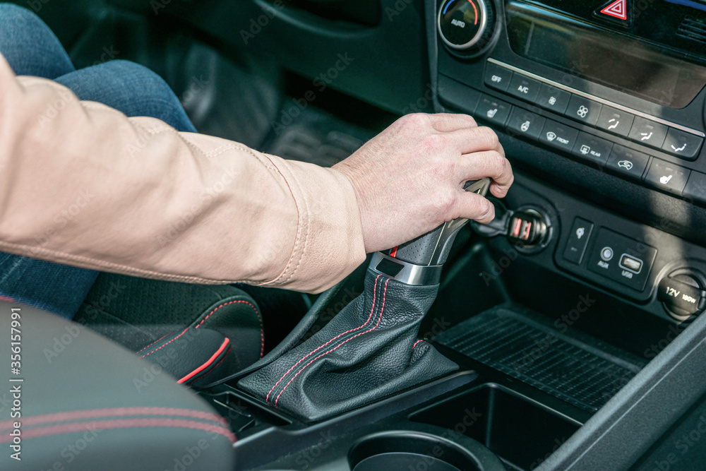 Woman's hands are shifting her gear knob in her new modern car.