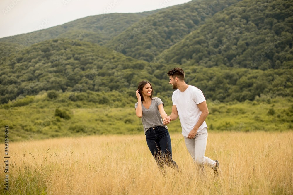 Happy young couple in love walking through grass field