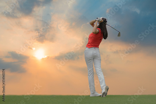 Lady golfer playing golf during beautiful sunset.