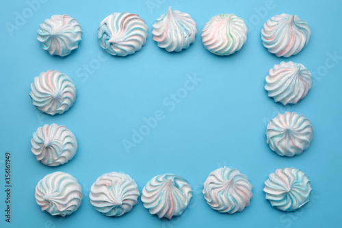 Frame made of colorful meringue cookies on blue background