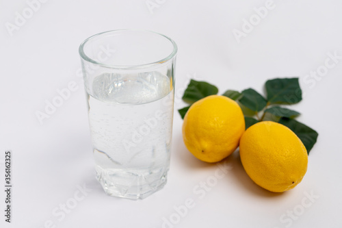 water in a glass with lemons on a white background, lemon water, a glass of water in the morning, healthy lifestyle, place for text