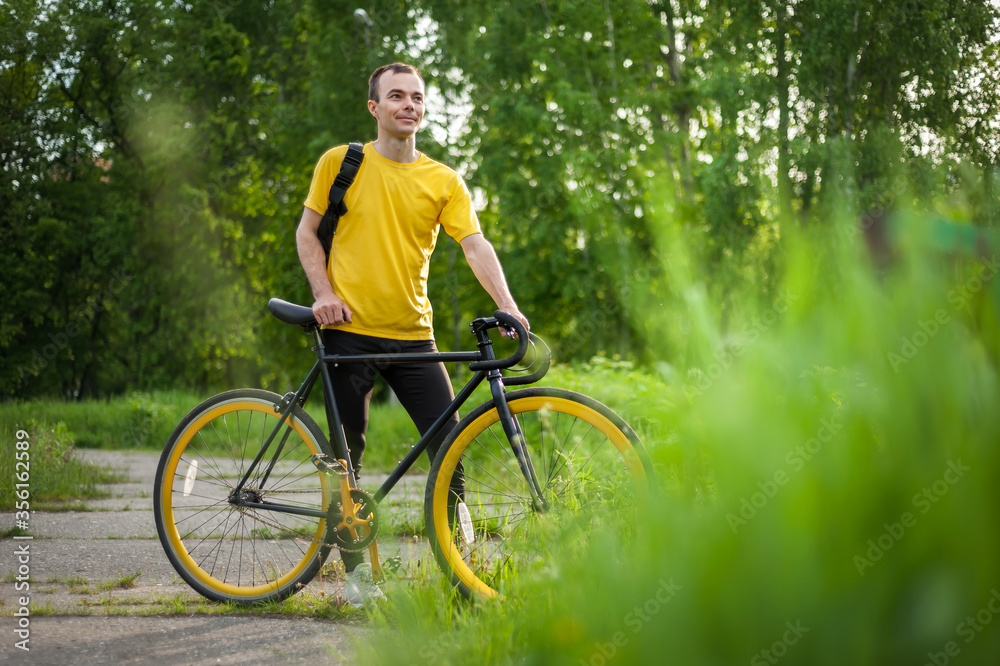A young Man stopped to rest With his Bicycle in a public Park.