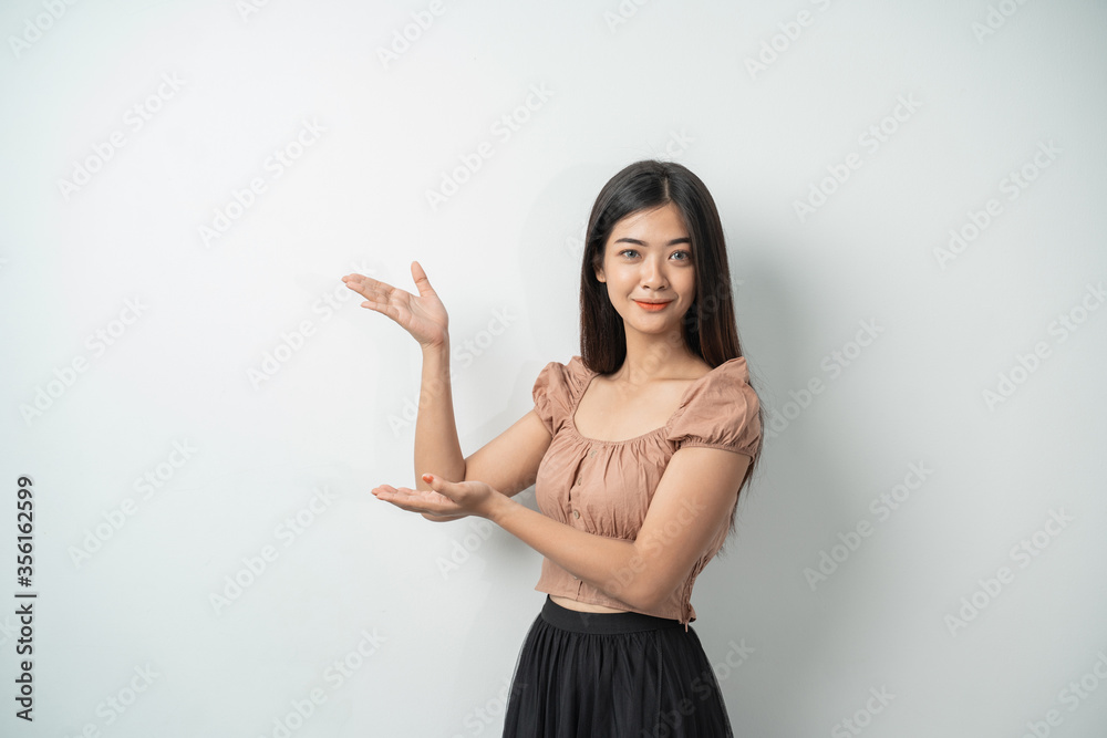 attractive woman with long hair standing up while hand gestures present something with an isolated background attractive woman with long hair standing up while hand gestures present something with an isolated background