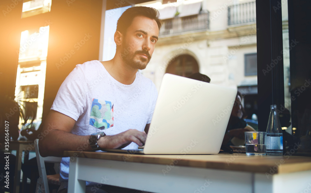 Young handsome man entrepreneur posing while sitting with open laptop computer Young handsome man entrepreneur posing while sitting with open laptop computer