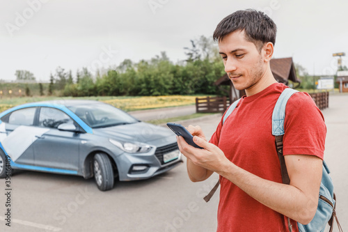 young person on a smartphone books a car or taxi in the carsharing app to get around the city. New generation chooses not to own a car but to rent a vehicle photo