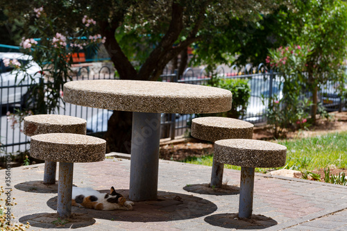 Old white stone marble circle chairs and table in a green garden 