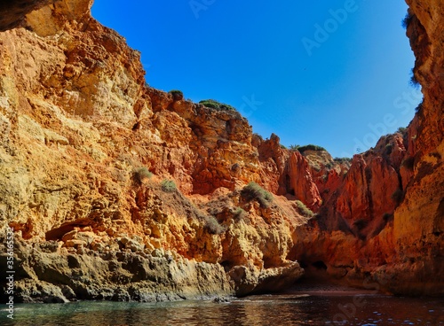 Sandstone Cliff Cave near Carvoeiro with calm Atlantic Ocean. Beautiful Sea Cave in Algarve Coast, with Cave Hole Showing Blue Sky.
