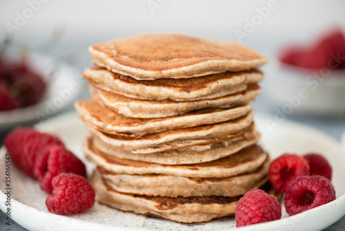 Stack of whole wheat pancakes with raspberries on plate, selective focus