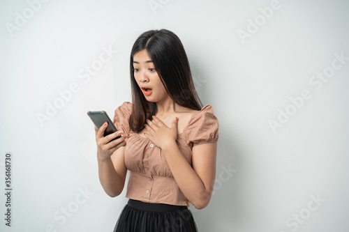 beautiful asian girl expression amazed when she saw the screen of a smart phone with an isolated background