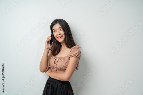pretty girl with long hair smile and standing using smart phone with an isolated background