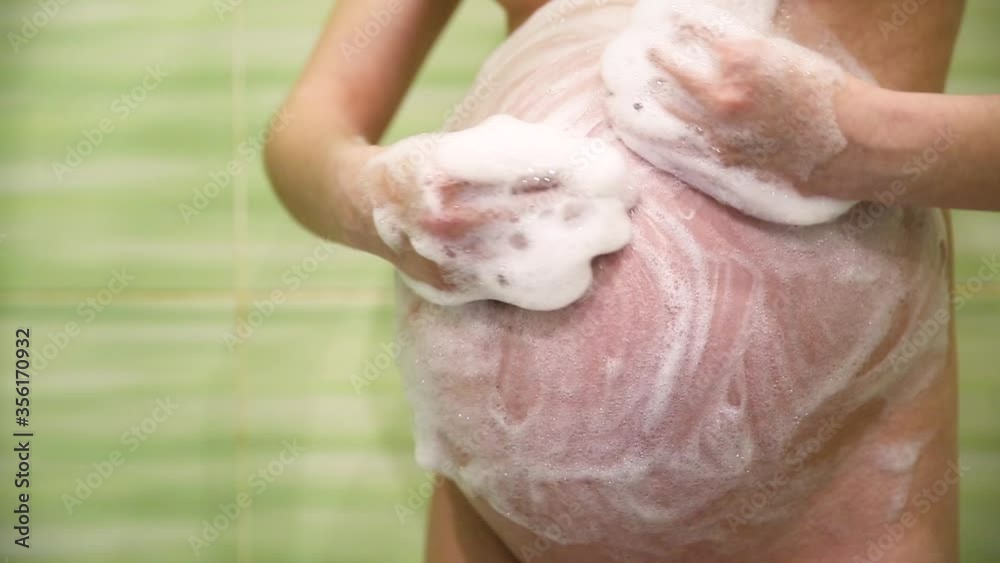 pregnant woman in the shower lathers a big belly under water pregnant woman in the shower lathers a big belly under water