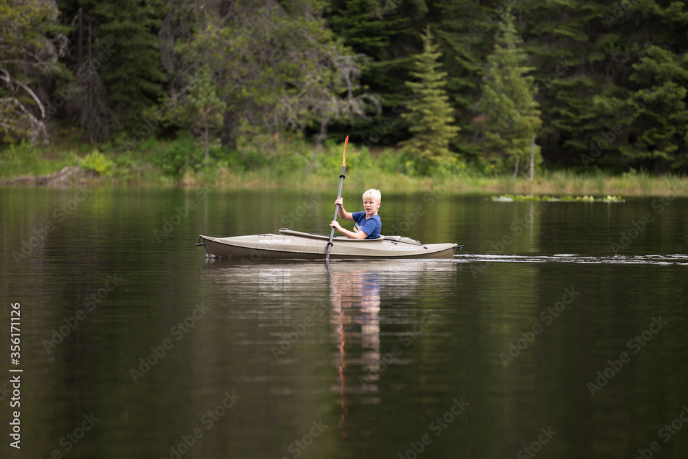 Boy kayaking on Moose Creek Reservoir in northern Idaho Boy kayaking on Moose Creek Reservoir in northern Idaho