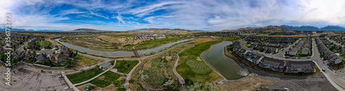 Panoramic aerial view of a river running through a suburb and golf course