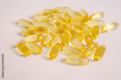 Fish oil capsules close-up. Omega nutrition, vitamin pills on neutral backdrop. Medical supplement tablets for vegan health care with empty space for text.
